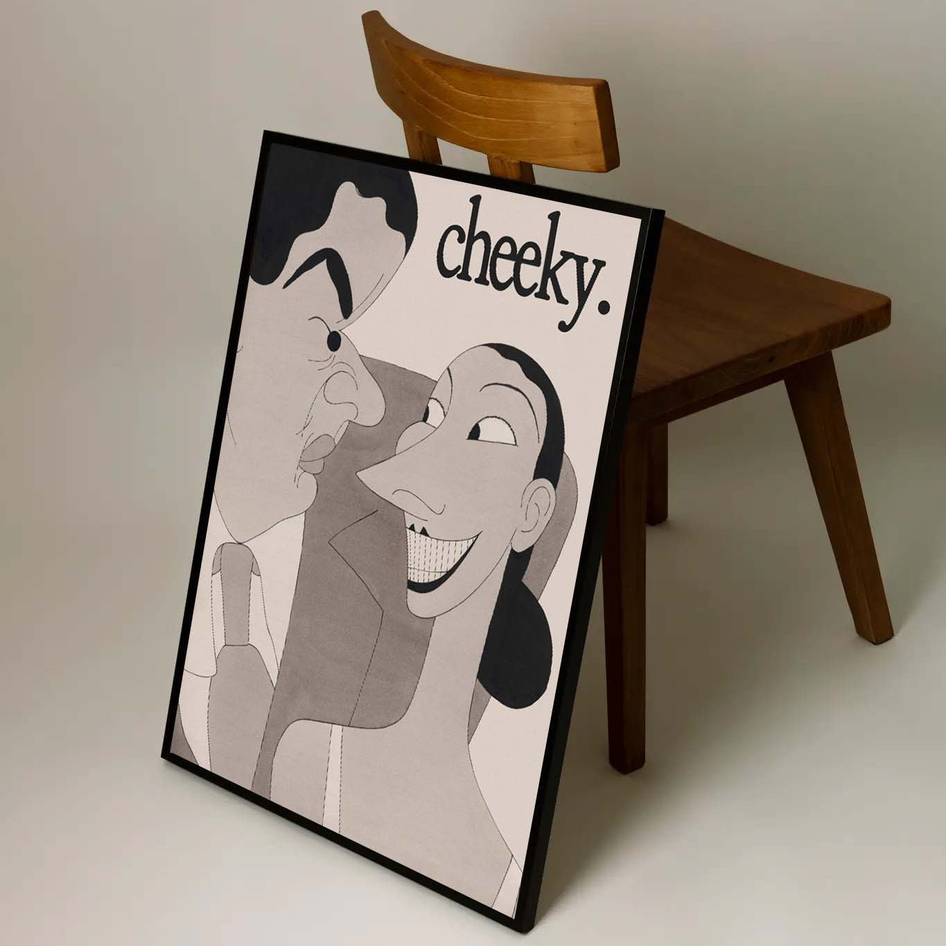 Framed artwork with cartoon characters and 'cheeky.' text on a table against a plain background